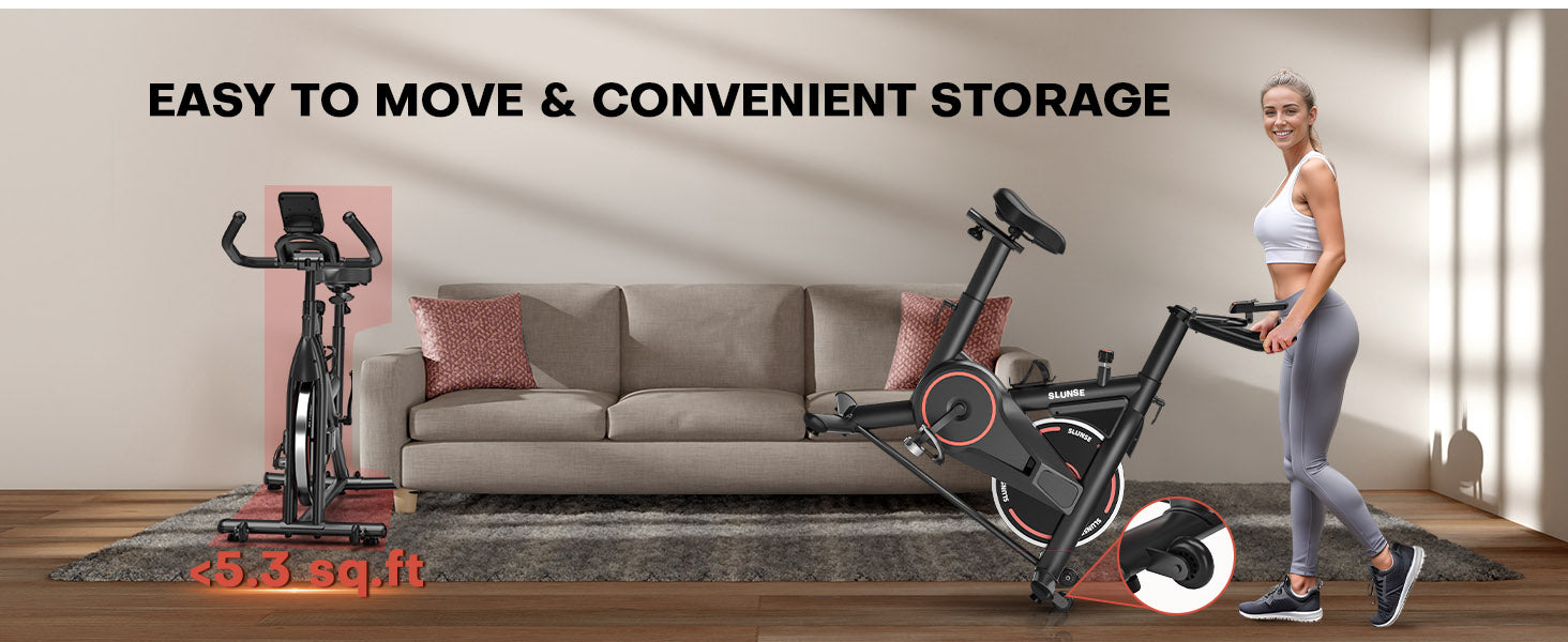 Un vélo d'appartement, une femme debout à côté, est posé sur un parquet dans un salon.